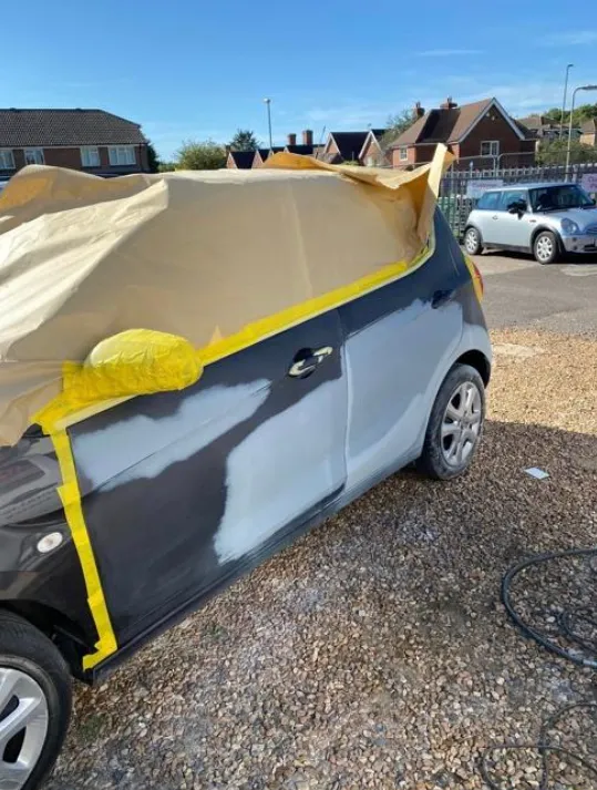 A car covered in a tarp in a parking lot.