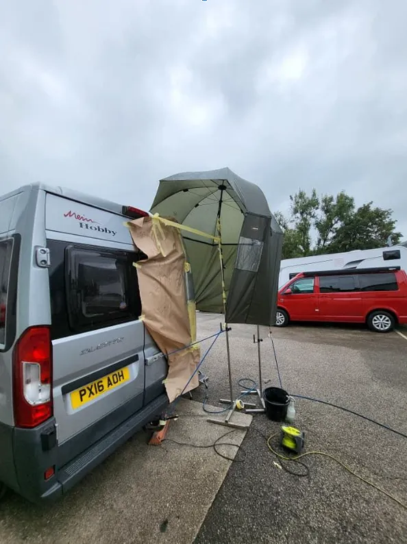A van is parked in a parking lot with an umbrella.